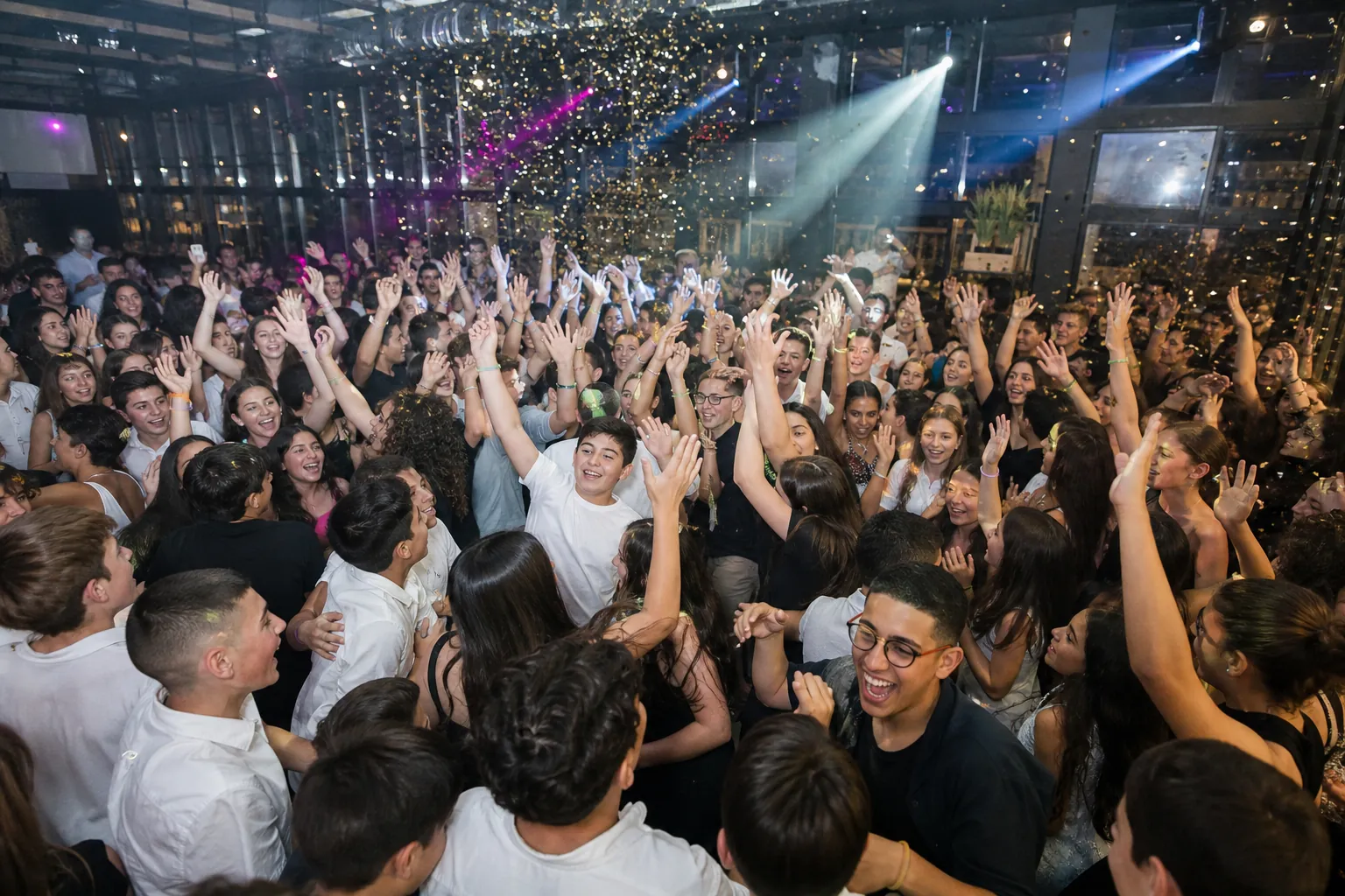 רחבה מלאה ילדים ובני נוער רוקדים ומרימים ידיים בבת מצווה