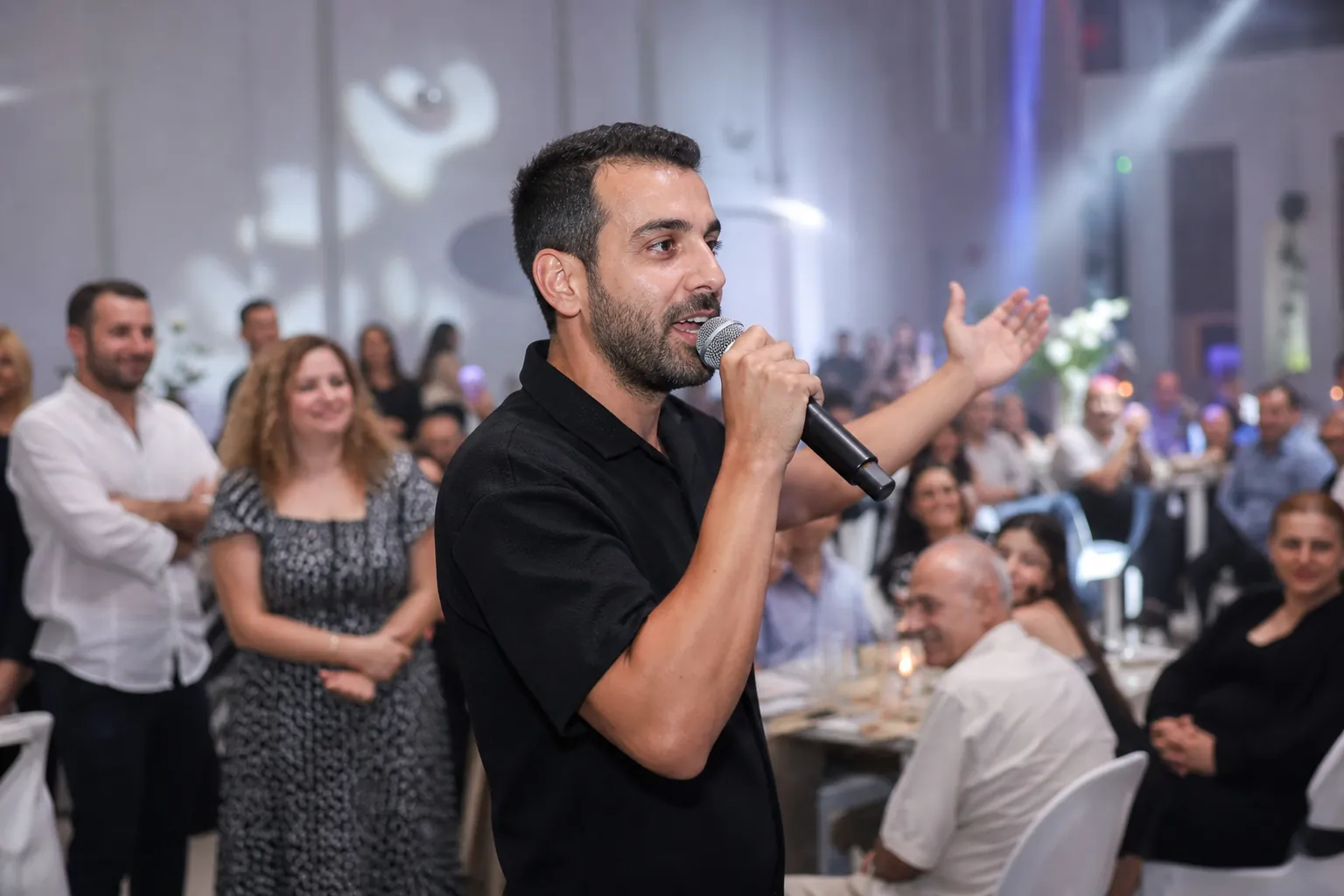 דיג׳יי מפעיל את הקהל עם מיקרופון בבת מצווה, אורות על הרחבה