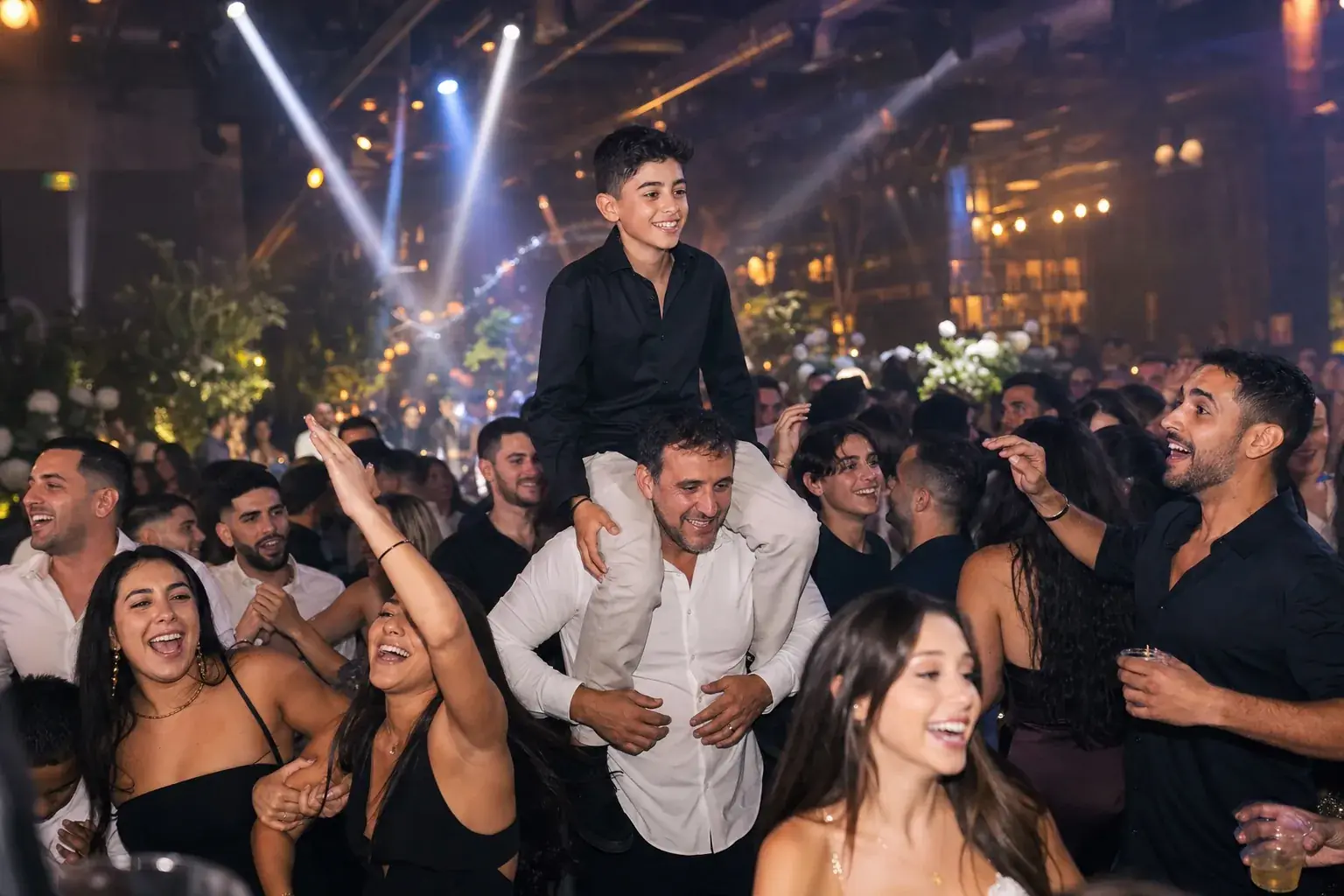 רחבה מלאה של ילדים רוקדים תחת תאורה לבנה וקרנ�י אור צבעוניות באירוע בר מצווה